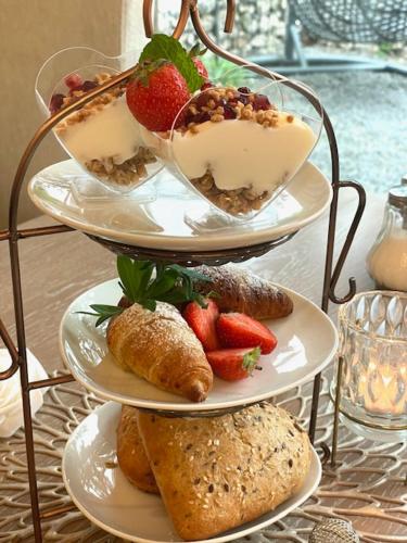 a three tiered display of pastries and strawberries on plates at Fichtenwald-Ihr Boutique I Glück`s Hotel in Bad Füssing