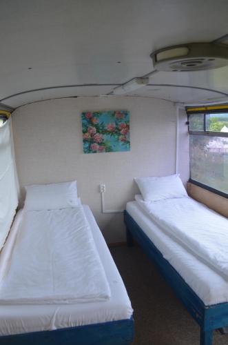 two beds in a small room with a window at La Busuri Camp in Roşia