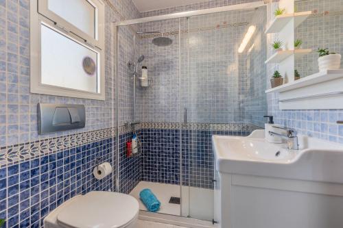 a blue tiled bathroom with a toilet and a sink at Casa Betta in Costa Calma