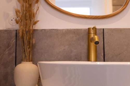 a bathroom sink with a gold faucet and a vase at Le Balinais - Avec Sauna et Balnéo in Dunkerque