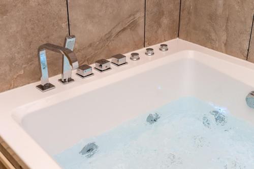 a white bath tub with a faucet in a bathroom at Le Balinais - Avec Sauna et Balnéo in Dunkerque