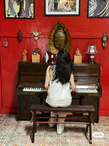 a girl sitting on a bench in front of a piano at Bitterswiit Ladies Hostel in George Town