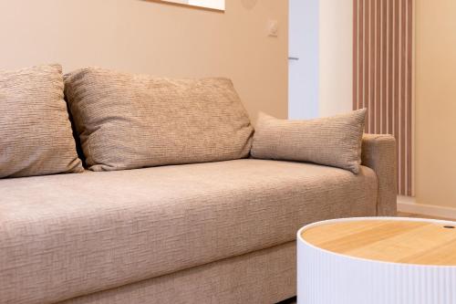 a brown couch in a living room with a table at Le Balinais - Avec Sauna et Balnéo in Dunkerque