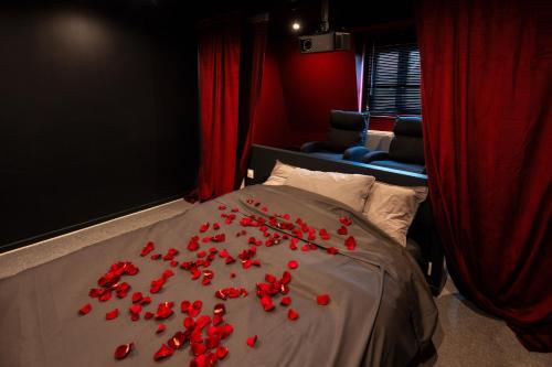 a bed with red rose petals on it at Le Grand Ecran - Studio Ambiance Cinéma in Dunkerque