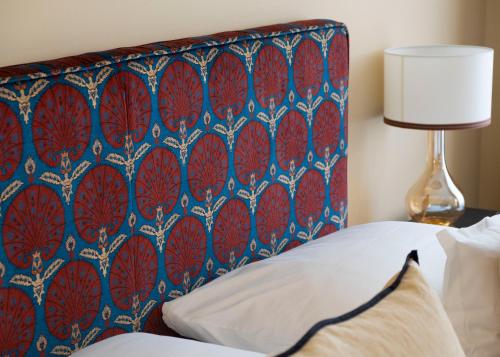 a bed with a blue and red headboard with a lamp at Roosevelt Stadthaus in Vienna