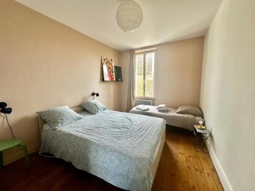 une chambre avec deux lits et une fenêtre dans l'établissement La courette, maison avec cour proche plage, à Graye-sur-Mer