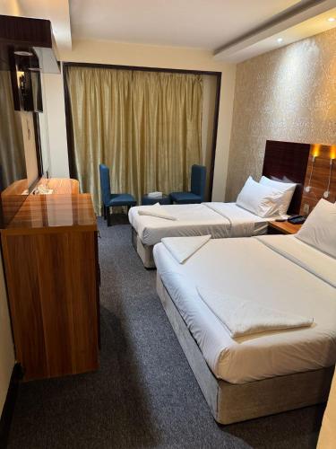 a hotel room with three beds and a desk at Akasiya Hotel - Formerly known as Fal Hotel in Dubai