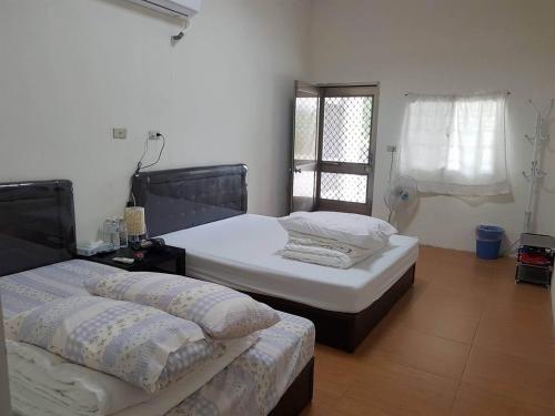 two twin beds in a room with a window at Taitung Luye Qitai B&B in Luye
