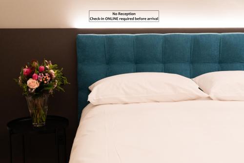 a vase of flowers sitting next to a bed at Arbed Living Hotel SELF CHECK IN - Supercharger - Fitness Bellinzona in Bellinzona