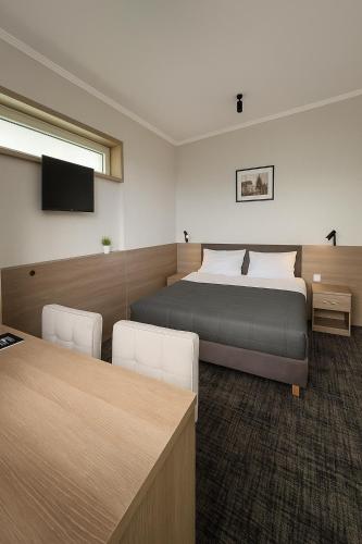 a bedroom with a bed and a desk and a tv at Willa Zdrojowa PARK Sauna, Jacuzzi, Fitness in Busko-Zdrój