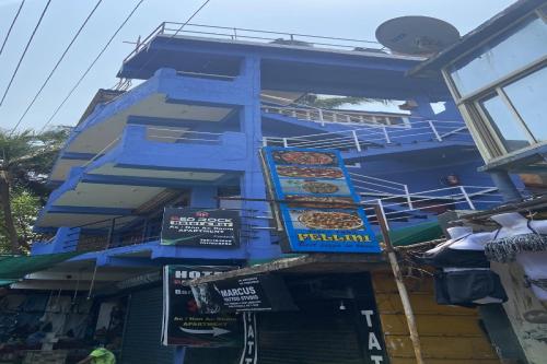 a blue building with signs on the side of it at Hotel O Red Rock Guest House in Arambol