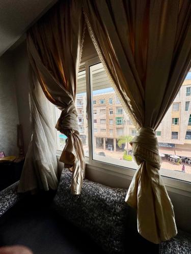two curtains in a room with a window at Wifak beach rental in Temara