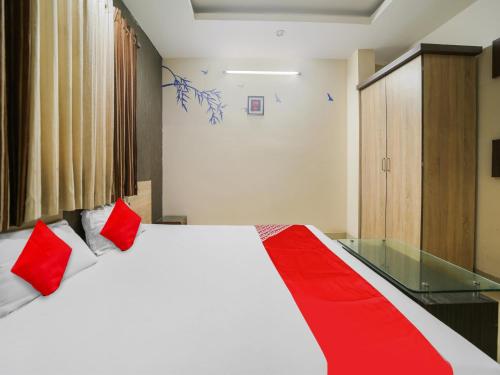 a bedroom with a large bed with red pillows at Hotel O New Om Palace in Bhopal