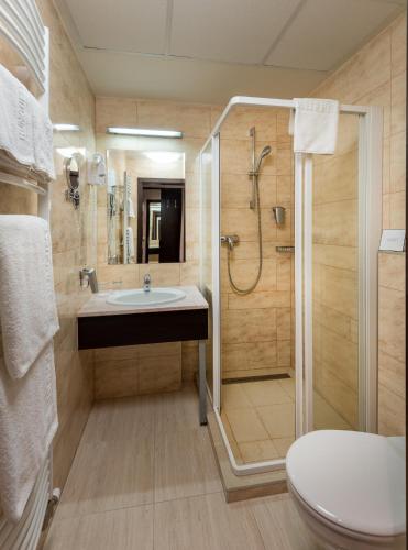 a bathroom with a shower and a sink and a toilet at Hunguest Hotel Gyula in Gyula