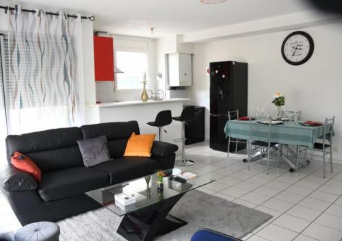 a living room with a black couch and a table at Appartement lumineux et spacieux à Bordeaux ! in Bruges