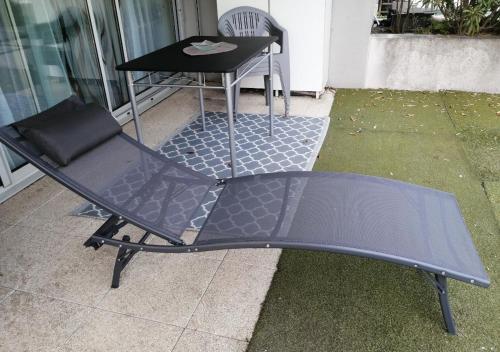 a black chair and a table on a patio at Appartement lumineux et spacieux à Bordeaux ! in Bruges