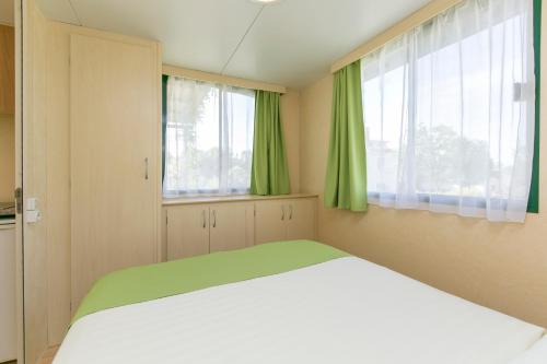 a bedroom with a large bed with green curtains at Mobile Homes Romantik in Labin