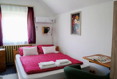 a bedroom with a red bed with towels on it at Mézeskuckó in Tiszaszőlős