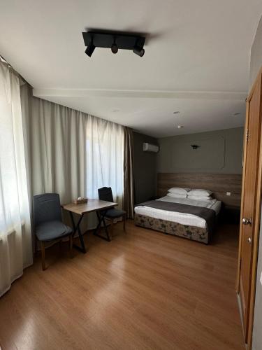 a bedroom with a bed and a table with chairs at Hotel Gloria Standard in Borovoye