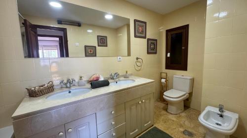 a bathroom with two sinks and a toilet at Apartamento Playa San Juan con vistas By ElConserje in Alcázar de San Juan