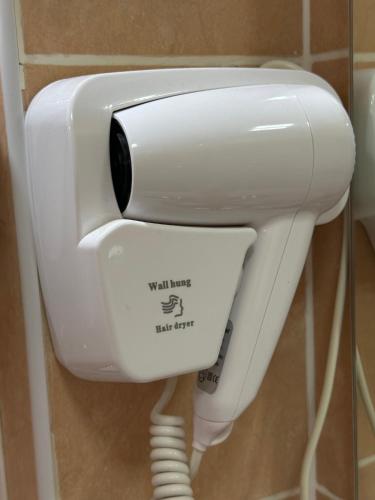 a white toilet in a bathroom with a hair dryer at Hotel Gloria Standard in Borovoye