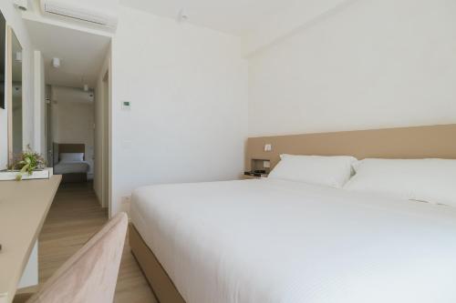 a bedroom with a large white bed and a bathroom at Maison Sirolo in Sirolo