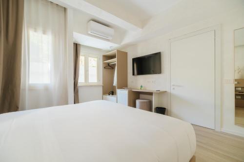 a white bedroom with a white bed and a television at Maison Sirolo in Sirolo