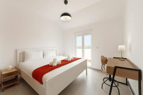a white bedroom with a large bed and a desk at Baleal Oceanviews in Ferrel