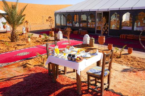 a table with food on it in front of a tent at Young Luxury Camp Merzouga in Merzouga