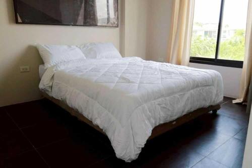a bed with a white comforter in a bedroom at RQ Bangkok Sukhumvit 107 by Collection O in Samut Prakan