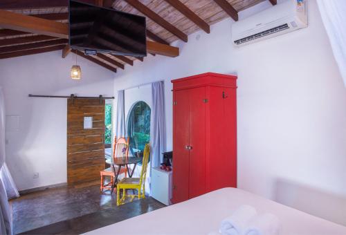 a bedroom with a red cabinet and a chair at Hotel Vila Kebaya in Ilhabela