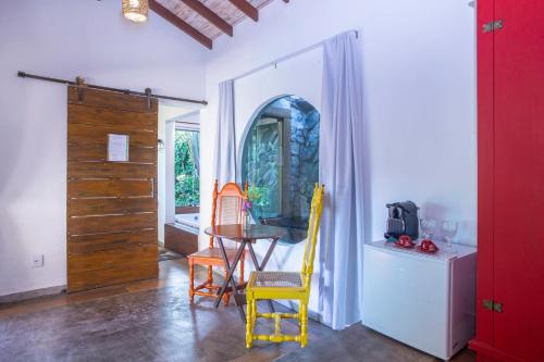 a dining room with a table and yellow chairs at Hotel Vila Kebaya in Ilhabela