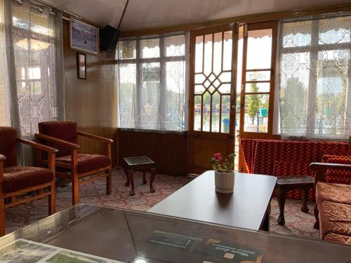 a room with a table and chairs and windows at Movie land group of house boats in Srinagar