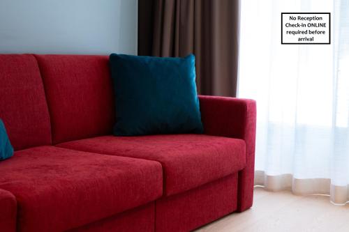a red couch with a blue pillow in a room at Arbed Living Hotel SELF CHECK IN - Supercharger - Fitness Bellinzona in Bellinzona