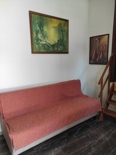 a red couch against a white wall with a painting at Accommodation in Lithi in Chios