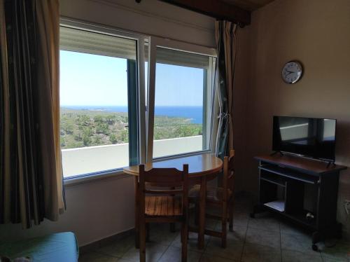 a room with a table and a television and a window at Accommodation in Lithi in Chios