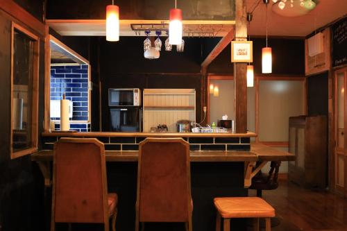 a kitchen with a bar with chairs and a table at WAVILLA mihata cho in Yamagata