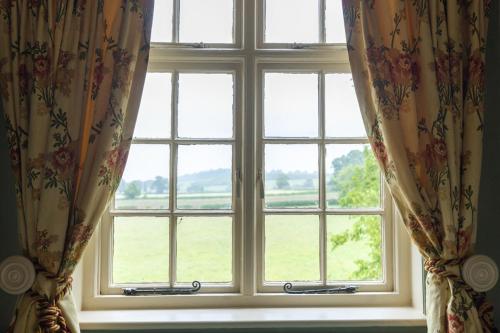 a window with curtains with a view of a field at The Manners Sleeps 20 Private Bar Dining in Croxton Kerrial