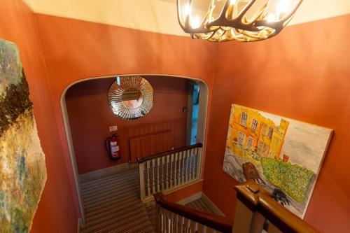 a room with an orange wall with a mirror and a staircase at The Manners Sleeps 20 Private Bar Dining in Croxton Kerrial
