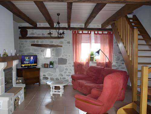 un soggiorno con un divano rosso e una TV di Gite le Marronnier a Saint-Mamet-la-Salvetat