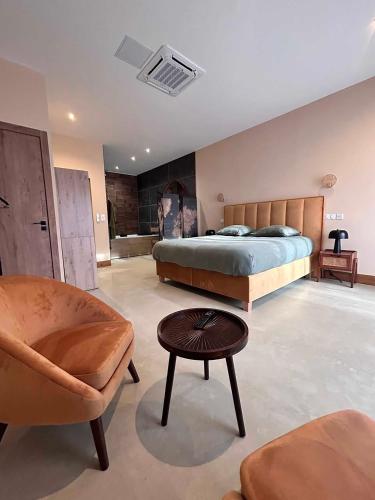 une chambre avec un lit, une chaise et une table dans l'établissement La Maison Coloniale Suites privatives de luxe, à Torreilles