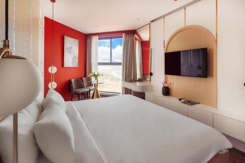 a bedroom with a white bed and a tv at Golden Sands Bayfront Mũi Né in Mui Ne