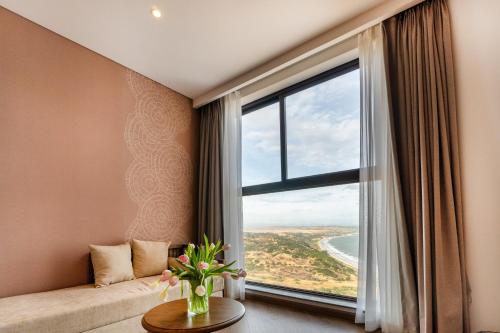 a room with a large window with a couch and a table at Golden Sands Bayfront Mũi Né in Mui Ne