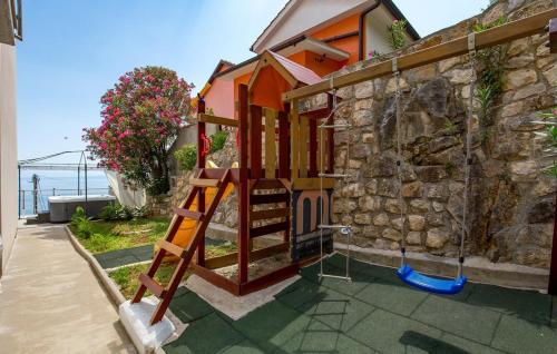 a house with a playground next to a stone wall at Apartman Zora 3 by Villas guide in Mošćenice