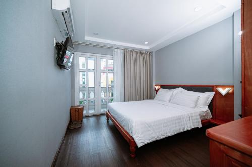 a bedroom with a white bed and a window at PH Hotel Near SECC Phu My Hung in Ho Chi Minh City