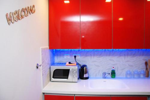 a kitchen with red cabinets and a microwave on a sink at City Apartments in Eilat