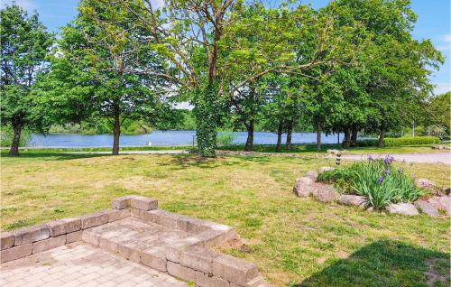 a stone bench in a park with trees and water at 2 Bedroom Cozy Home In Munka-Ljungby in Munka-Ljungby