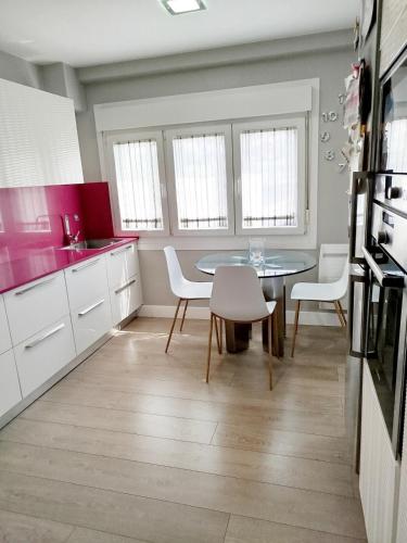 a kitchen with a table and chairs and pink counters at Areal de Esteiro in Esteiro-Muros
