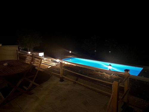 a swimming pool at night with a table and chairs at Casa Madrina, L'hacienda de Soubran, classé 4 étoiles in Soubran