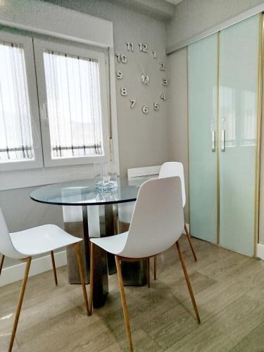 a dining room with a glass table and white chairs at Areal de Esteiro in Esteiro-Muros